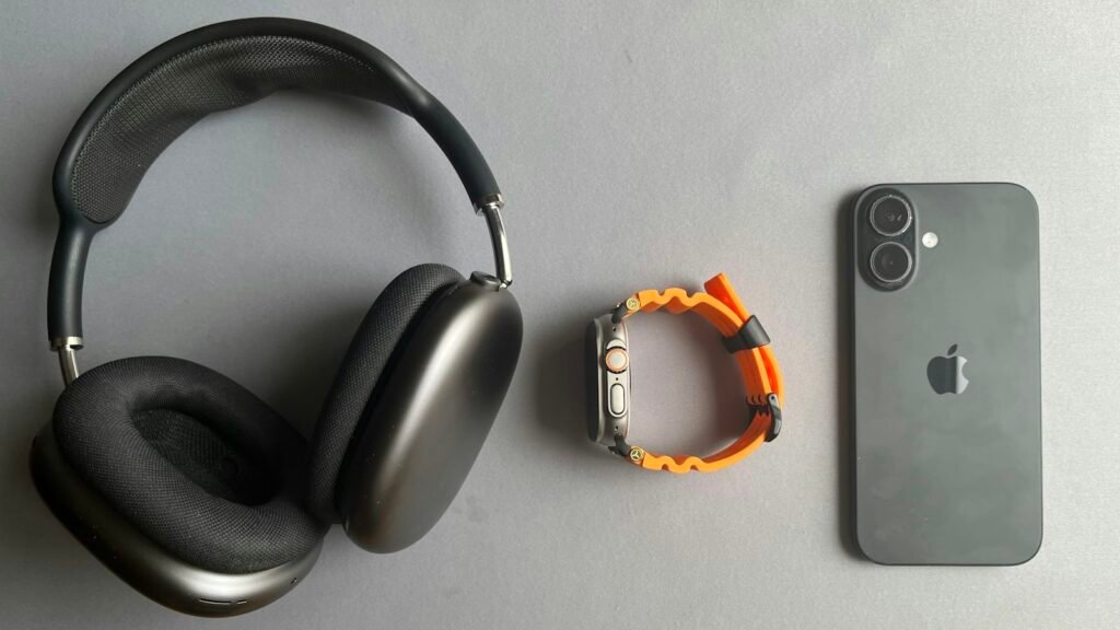 Casque audio noir, montre connectée et smartphone sur fond gris