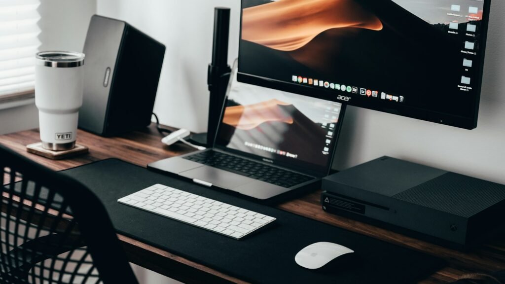 Espace de télétravail avec ordinateur portable, écran et clavier sur un bureau en bois
